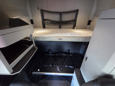 Kenworth T680 sleeper cab interior showing cargo area and bunk with storage compartments visible.