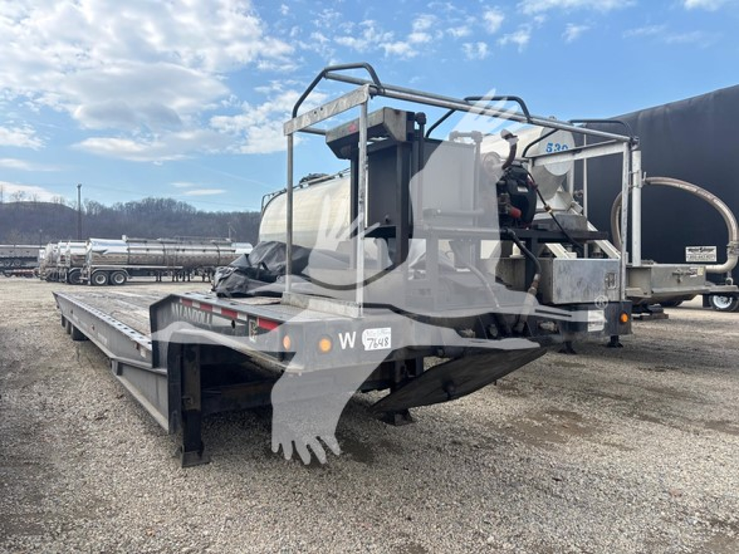 Landoll 440B trailer at a loading site, side and rear view showing long flatbed with dual axles, rear ramps, and overhead guard; visible VIN tag and stock number.