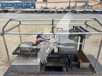 Trailer platform with winch and control box showing steel rails and battery box on a Landoll 440B trailer, metal frame, hydraulic components visible.