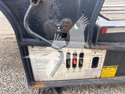 Landoll trailer rear with operation placard and control labels showing trailer operation, dock leveler, and wiring harness; rusted mounting plate visible.