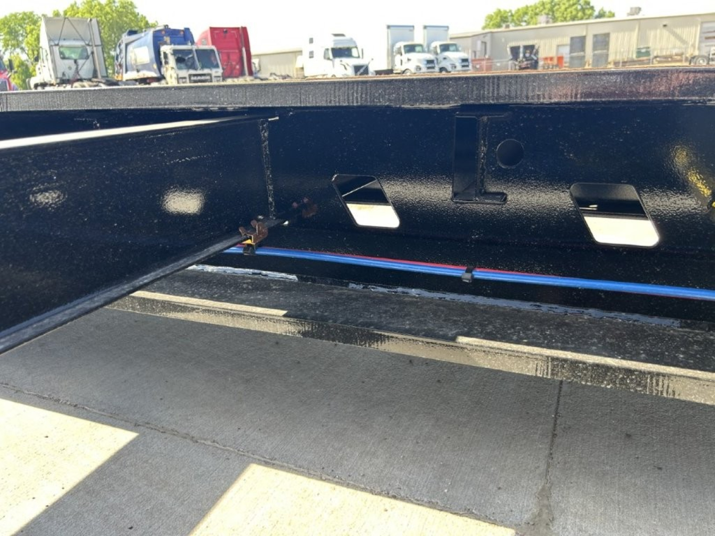 Trailer undercarriage showing welded steel frame with labeling holes and a blue line along the frame, HDG finish visible.