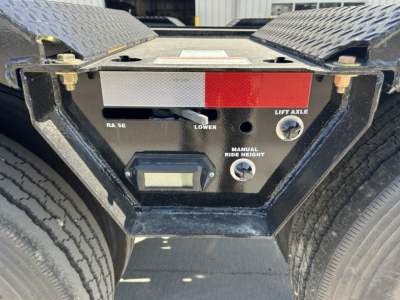 Heavy equipment trailer landing gear control panel with red warning strip and labels: Lift Axle, Manual Ride Height, Lower, RA SE, a small digital display, and two circular controls.
