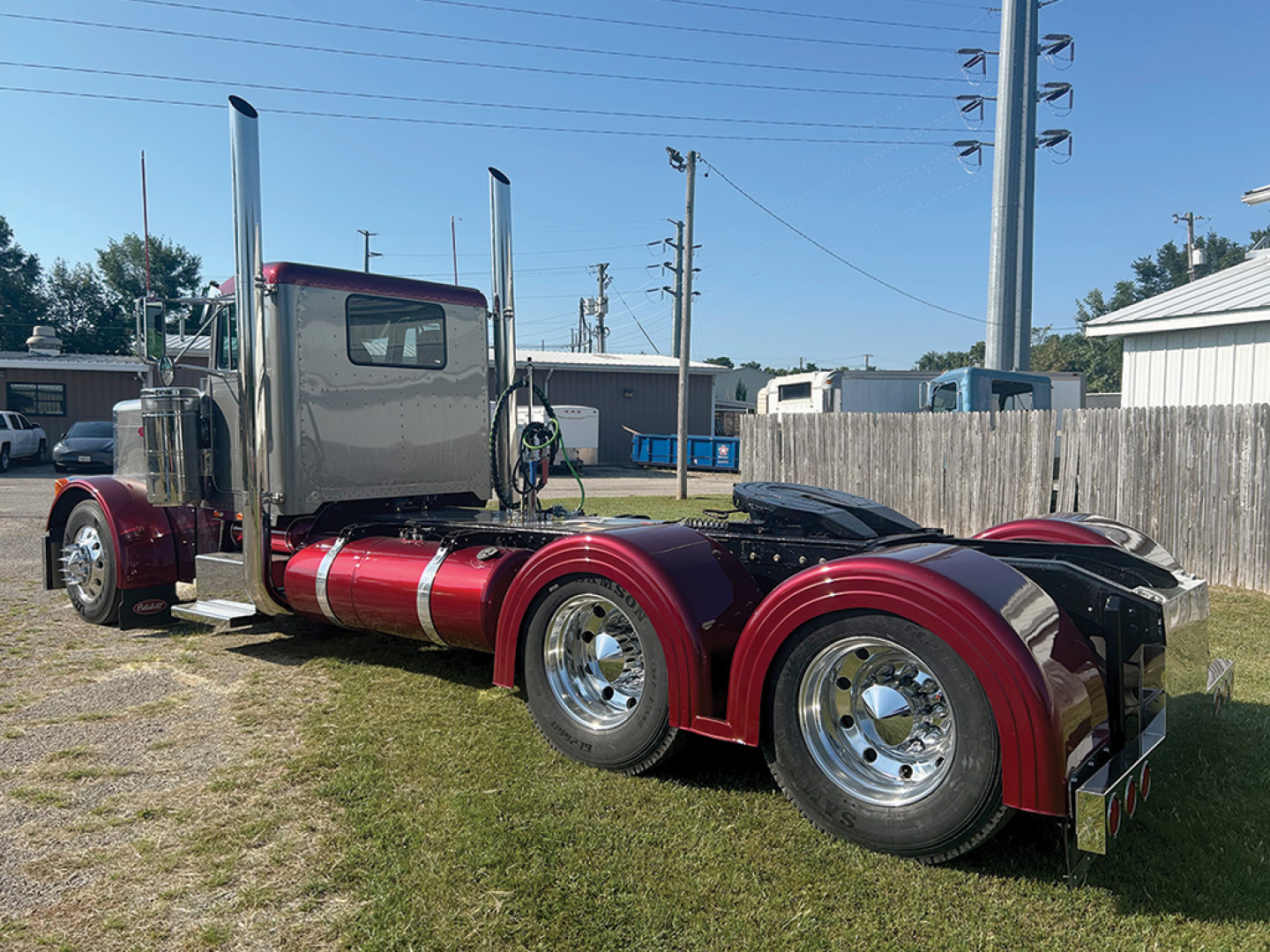 Peterbilt 379 conventional daycab tractor showing chrome exhaust stacks and maroon fenders with dual rear axles and polished wheels.
