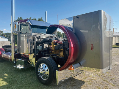 Peterbilt 379 conventional daycab truck with chrome cab and exposed engine, front wheel, and attached silver sleeper/box in background.