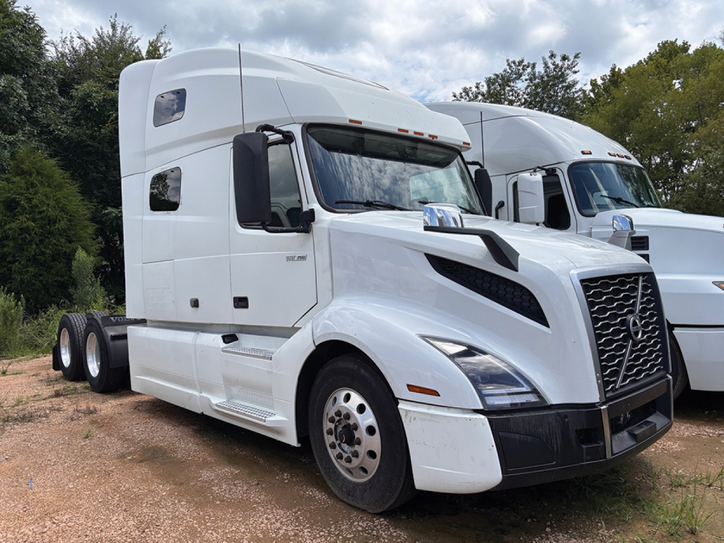 Tractor-trailer truck cab in white showing Volvo VNL 760 design with chrome grille, large windshield, sleeper cab, and dual rear axles.