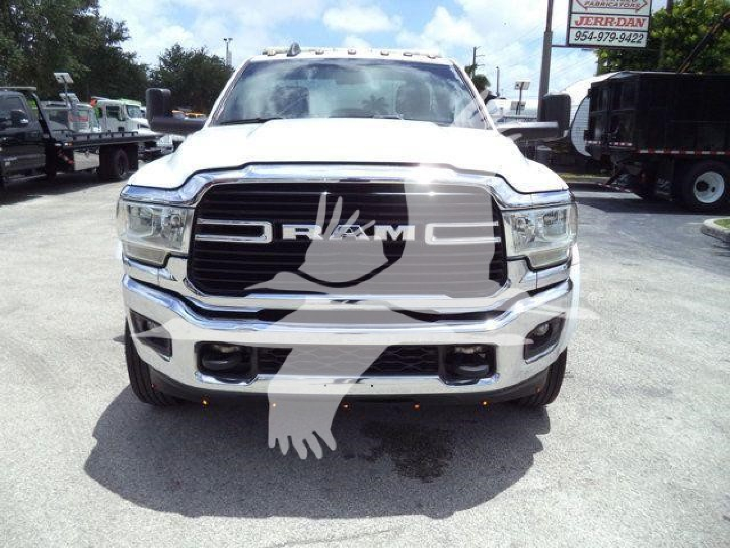 Ram 5500 front view showing chrome grille with RAM lettering and headlights, bumper with fog light openings; white body, tow mirrors, dealership lot in background.