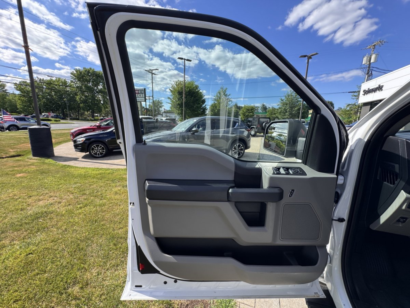 Ford F-150 2018 driver door interior view; light gray door panel, window and mirror controls, beige/gray trim, open front door