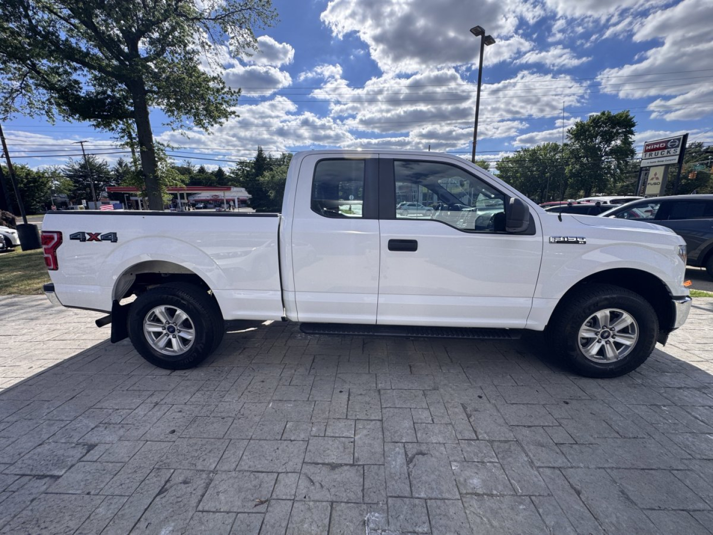 Side view of a white 2018 Ford F-150 pickup truck with extended cab, '4x4' badge on rear quarter, and alloy wheels.