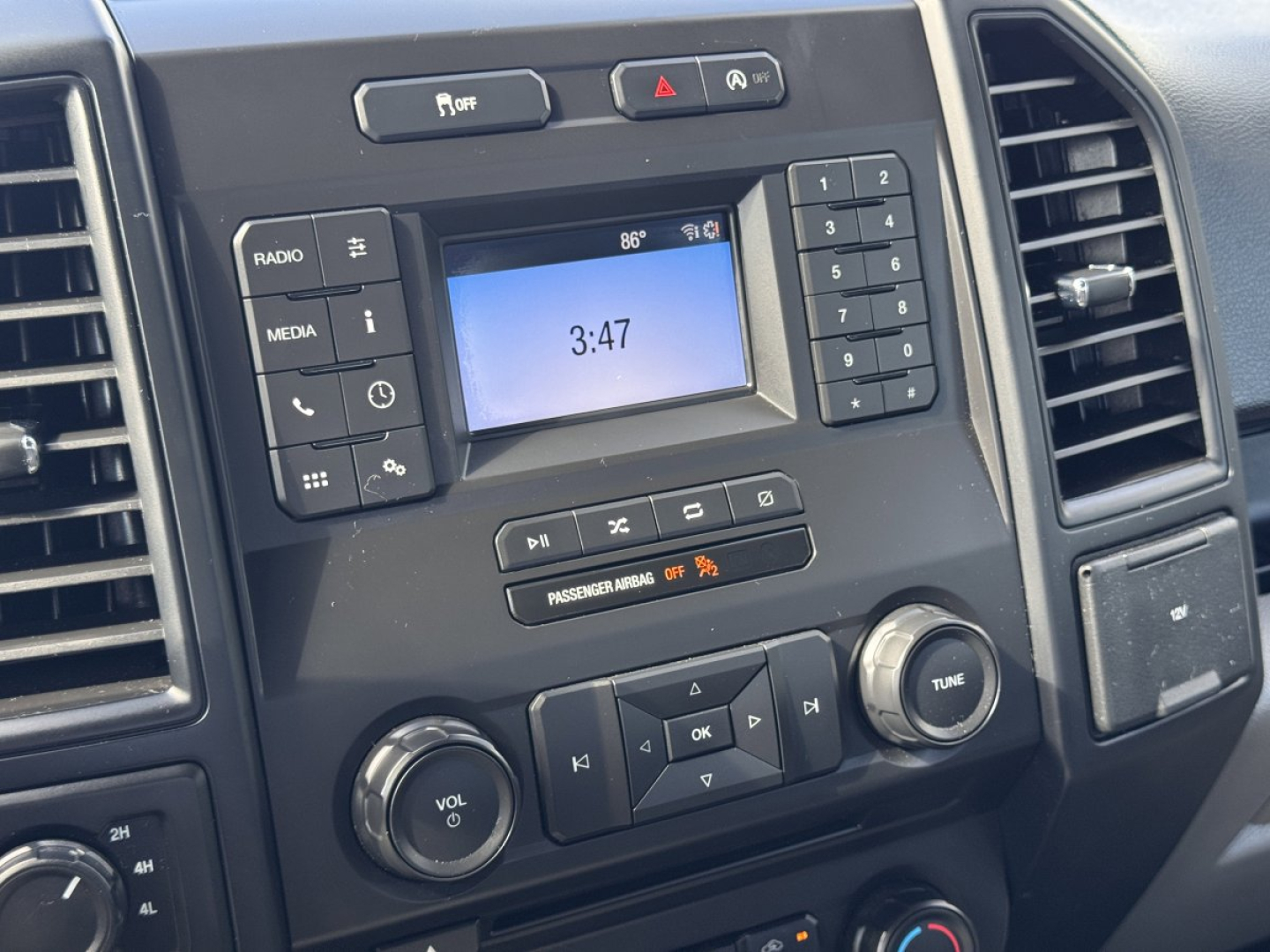 In-car dashboard of 2018 Ford F-150 showing center touchscreen, radio and media controls, climate dial, and other control buttons.