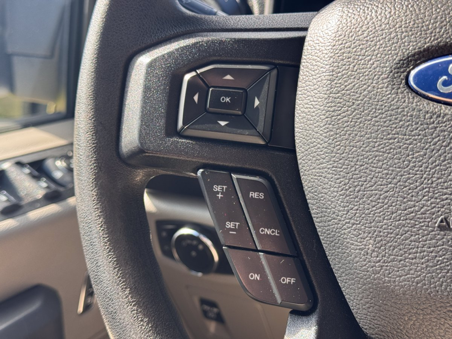 Ford F-150 steering wheel controls with OK button and cruise control pad visible.