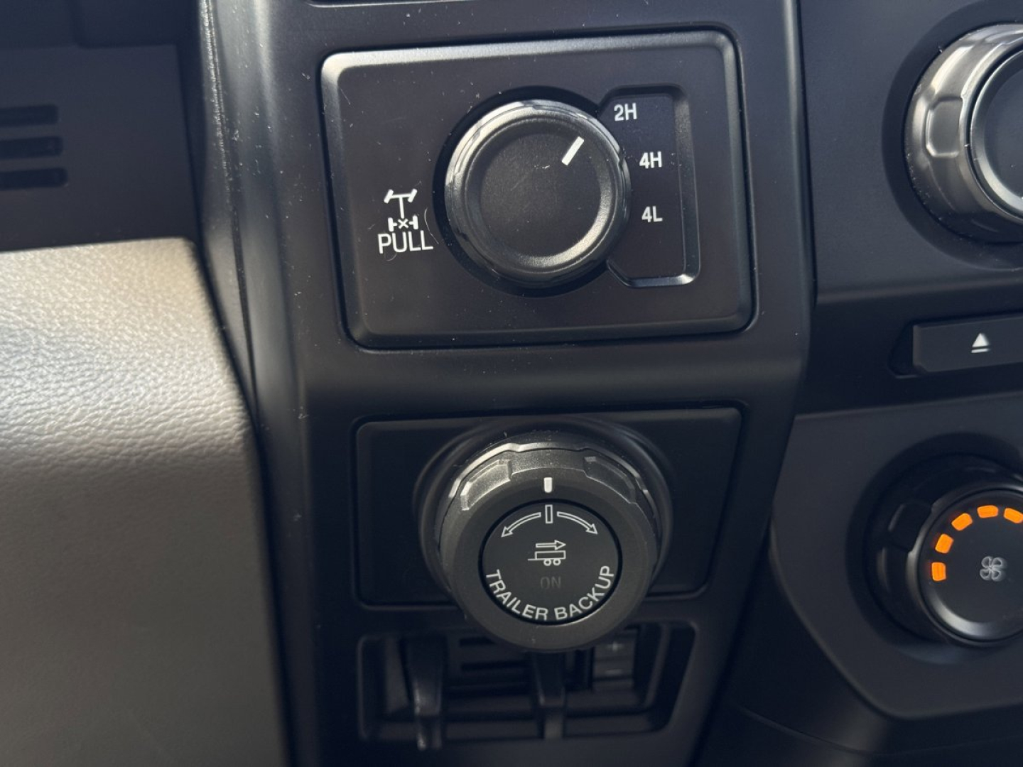 Ford F-150 dashboard switch panel showing trailer backup and drivetrain controls with 2H 4H 4L lock; knob and climate control visible.