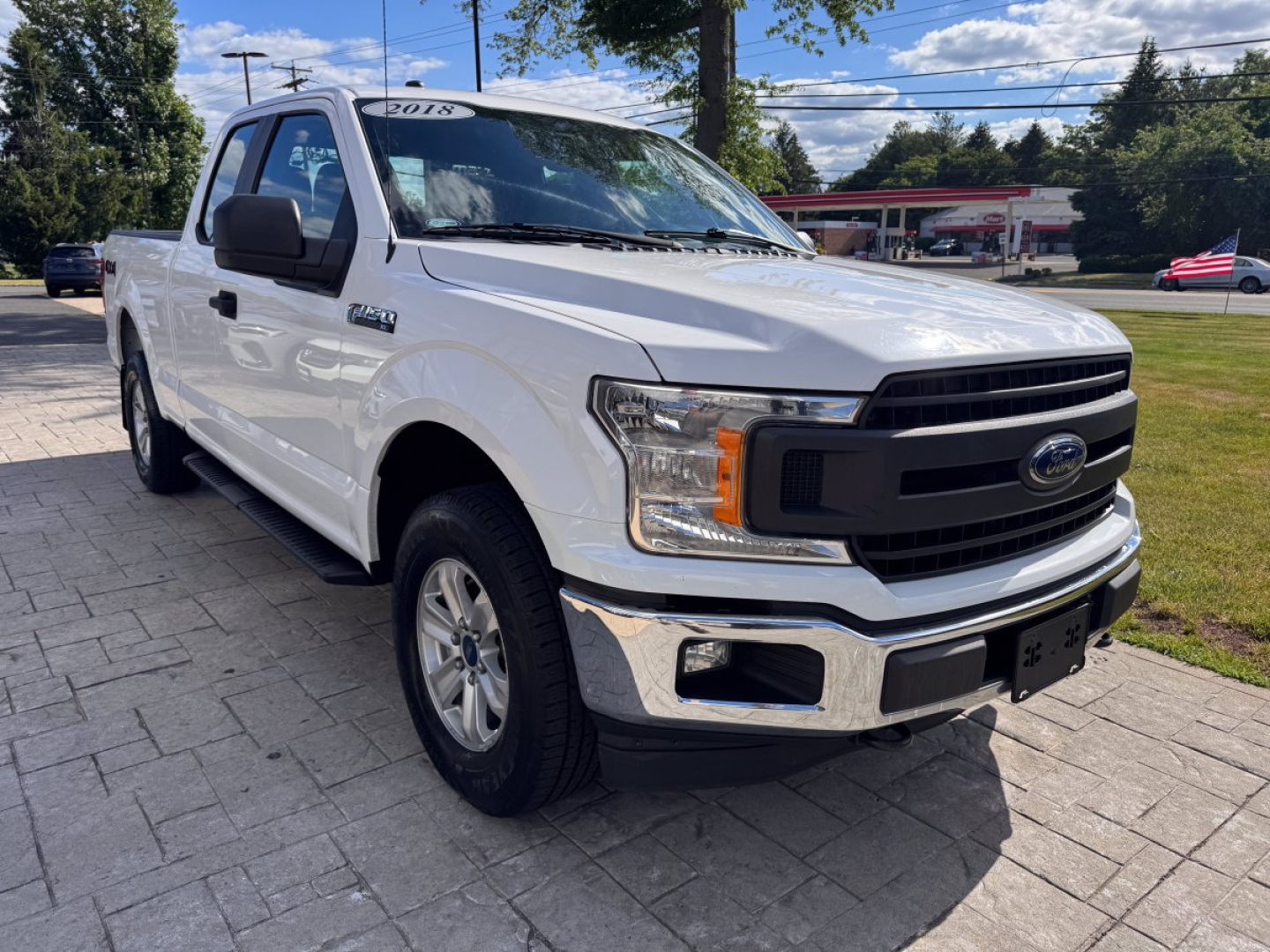 Ford F-150 pickup truck front-left view showing white body, black grille, chrome bumper, and large headlights.