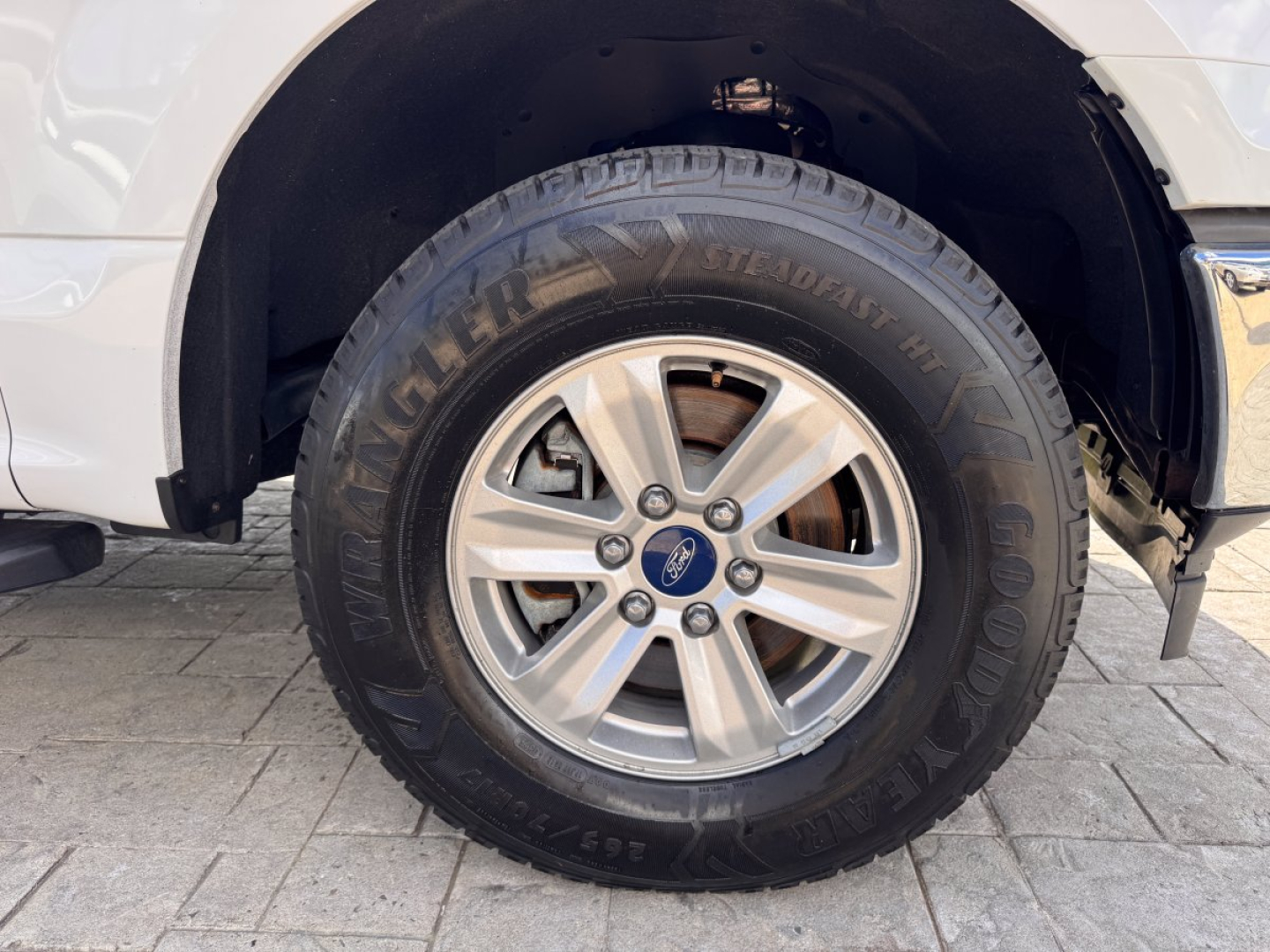 Ford F-150 front wheel and tire showing Hankook Dynapro AT-M tire and alloy wheel with Ford center cap in wheel well.