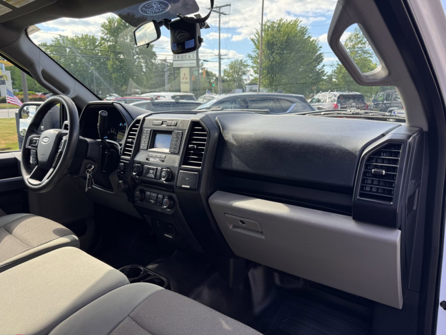Ford F-150 interior dashboard and steering wheel with center infotainment screen visible, front seats, and passenger side glove compartment.