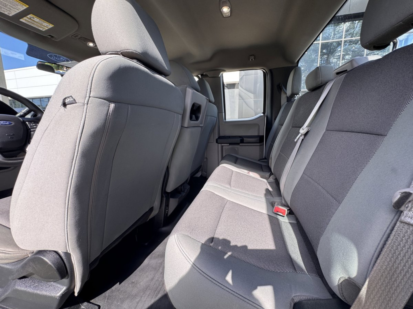 Ford F-150 interior rear seating view showing gray fabric upholstery and rear bench seat with three seat belts.