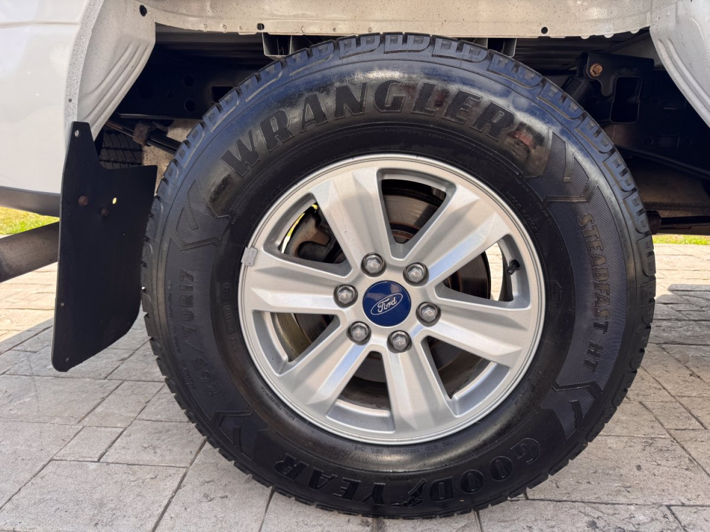 Ford F-150 wheel and tire close-up showing Goodyear Wrangler SR-A tire and alloy wheel with Ford center cap.