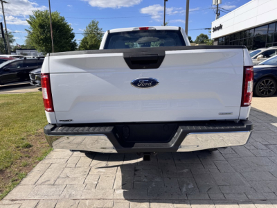 Ford F-150 tailgate view in white color with Ford emblem and rear bumper, 2018 model year, in a dealership lot.
