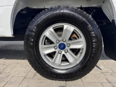Ford F-150 wheel and tire shown in-wheel well with alloy rim and all-terrain tire.