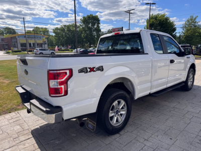 2018 Ford F-150 pickup truck rear three-quarter view with 4x4 badge on bed and stock number tag in rear window.