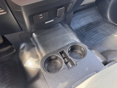 Ford F-150 cabin center console with two cup holders and a small storage slot, view of floor mats and lower dash area.