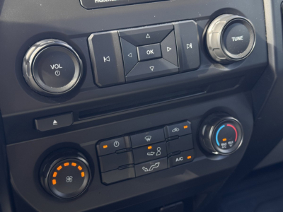 Ford F-150 dashboard view showing climate controls, radio control buttons, and knob labels.
