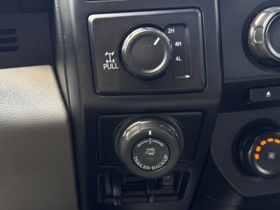 Ford F-150 dashboard switch panel showing trailer backup and drivetrain controls with 2H 4H 4L lock; knob and climate control visible.