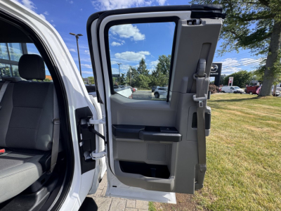 Truck door interior and open rear passenger door of a 2018 Ford F-150 showing grey interior panels and seatbacks, with the outside environment in a dealership lot.