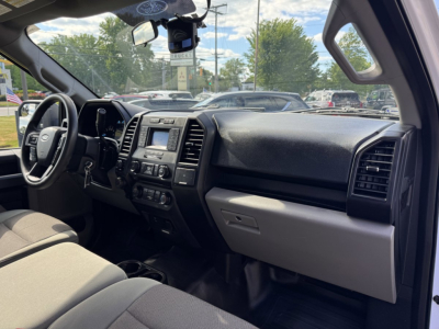 Ford F-150 interior dashboard and steering wheel with center infotainment screen visible, front seats, and passenger side glove compartment.