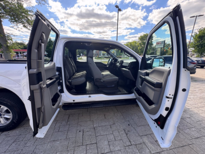 Ford F-150 interior passenger side and open doors showing front cabin with black seats and gray door panels.