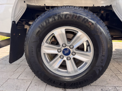 Ford F-150 wheel and tire close-up showing Goodyear Wrangler SR-A tire and alloy wheel with Ford center cap.