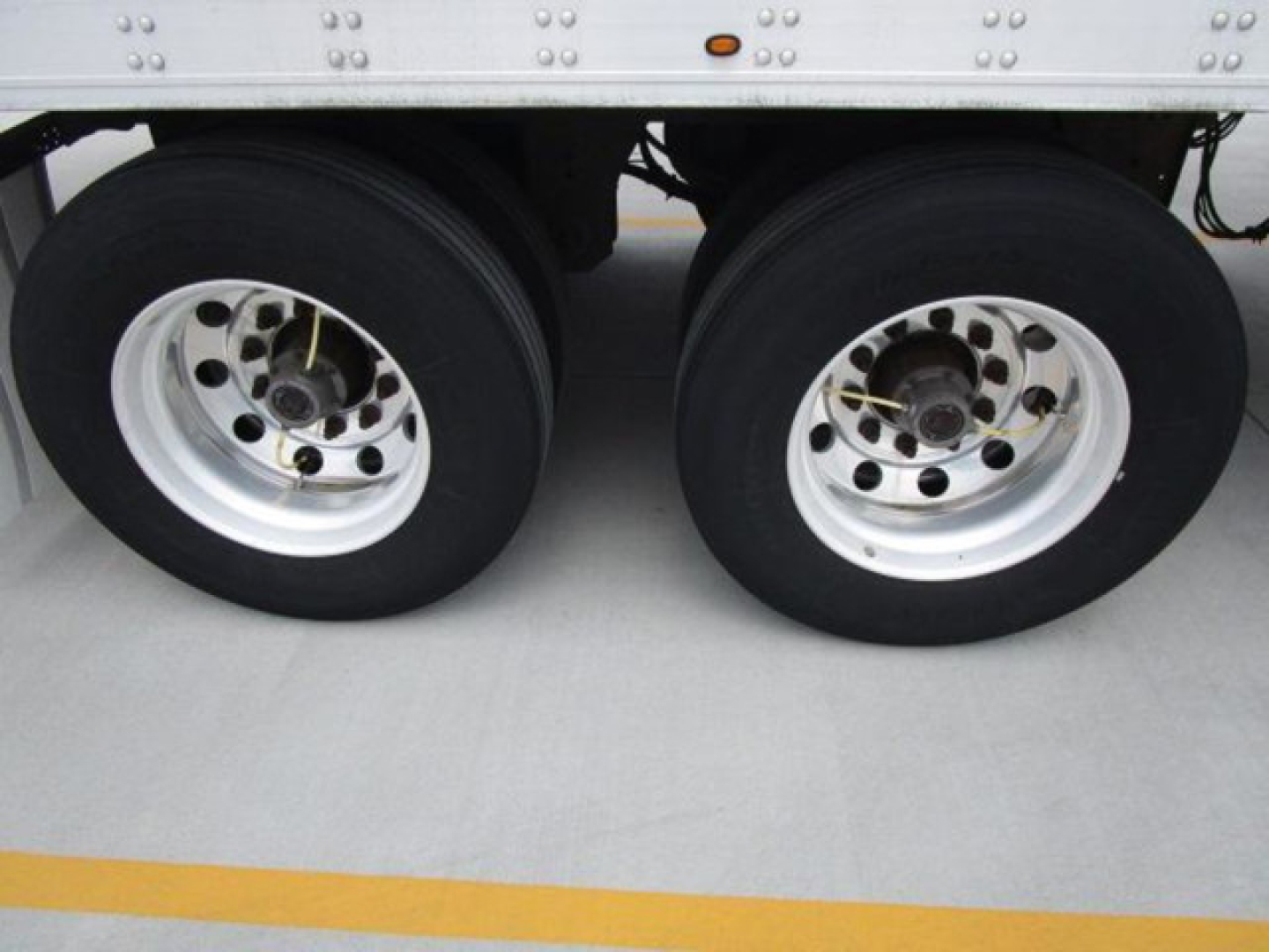 Dual rear wheels of a refrigerated trailer showing aluminum rims and black tires.