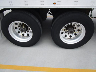 Dual rear wheels of a refrigerated trailer showing aluminum rims and black tires.