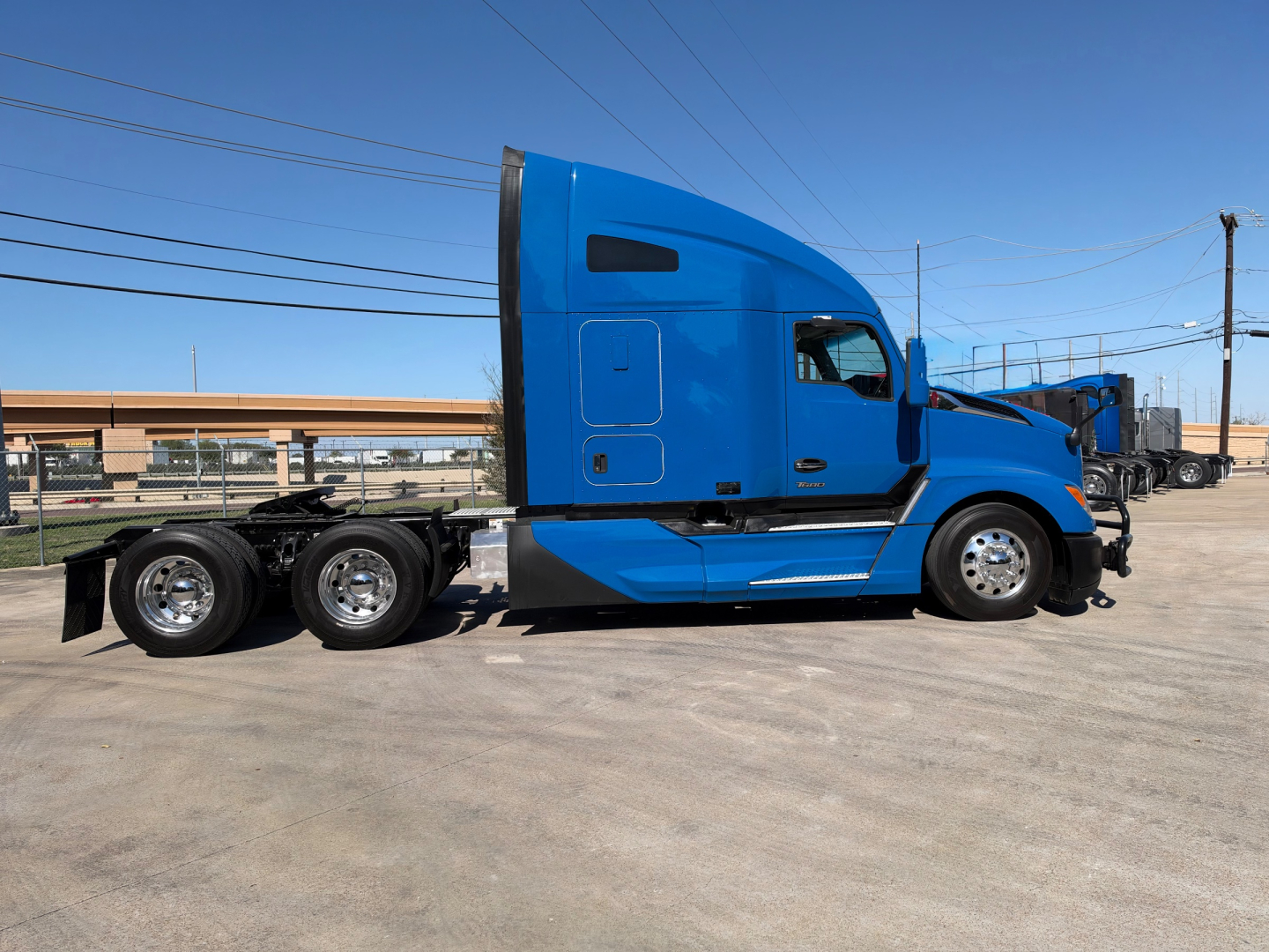 Kenworth T680 sleeper cab with blue exterior side view showing tractor chassis and rear dual axles.
