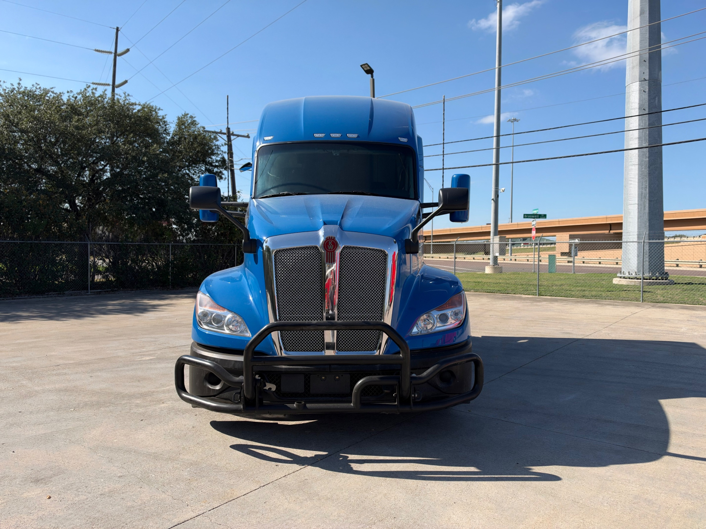 Kenworth T680 conventional sleeper truck front view with blue paint, grille guard, and chrome grille