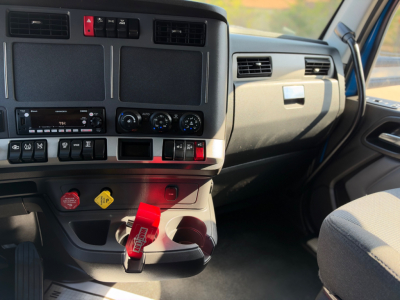 Kenworth T680 dashboard and center console view showing climate controls, cup holders, and ignition area.