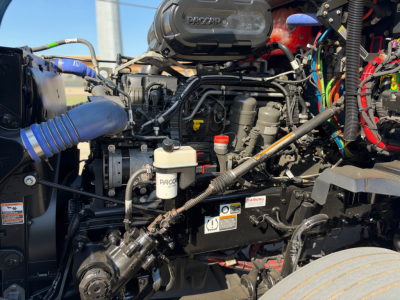 Kenworth T680 engine bay view showing air intake, various hoses, and wiring harnesses.