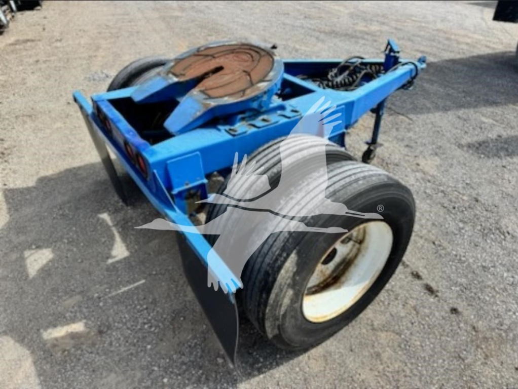 Blue Stoughton single-axle dolly trailer in-service with spare tire mount and hydraulic components visible.
