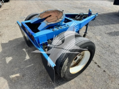 Blue Stoughton single-axle dolly trailer in-service with spare tire mount and hydraulic components visible.