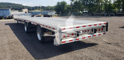 Big Bubba dropdeck trailer in a cargo lot showing dual rear axles and reflective safety stripes.