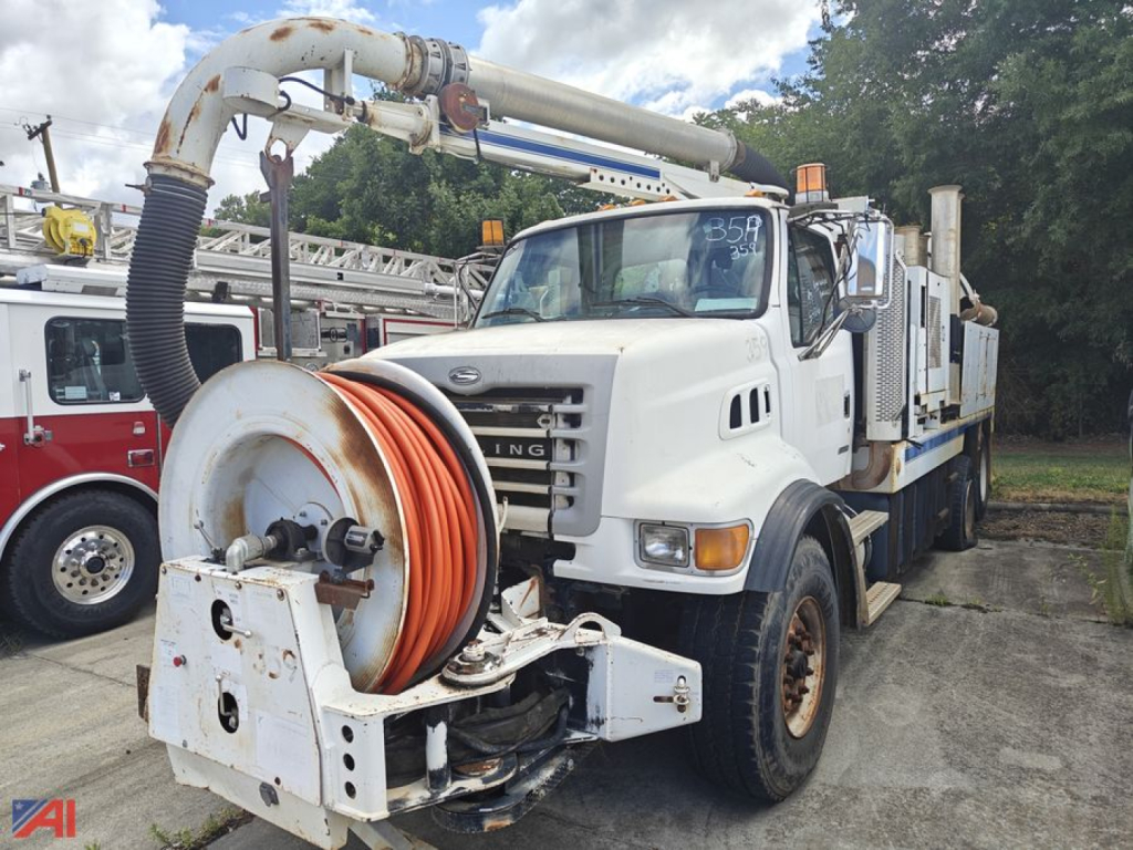 Sterling LT7500 Vac Con truck with large hose reel and vacuum boom in foreground.
