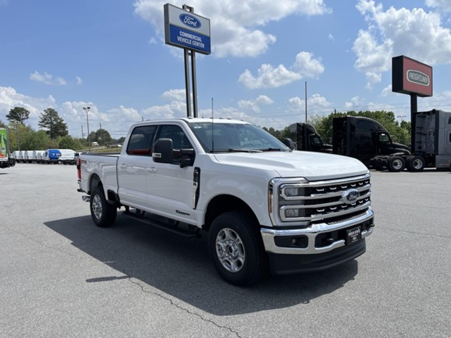 Front-left side view of a white 2026 Ford F-350 pickup truck in a dealership lot. The truck features a chrome grille, dual mirrors, running boards, and four doors with a long bed.