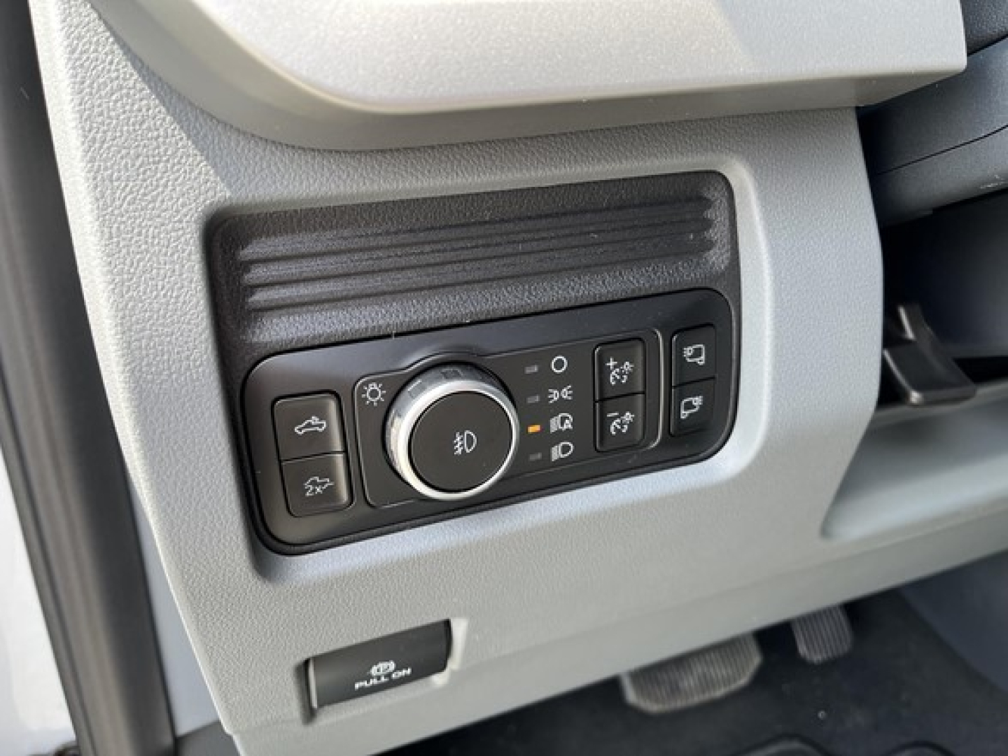 Ford F-350 dash panel showing headlight control stalk and buttons with icons for fog lights, brightness, and other lighting controls.