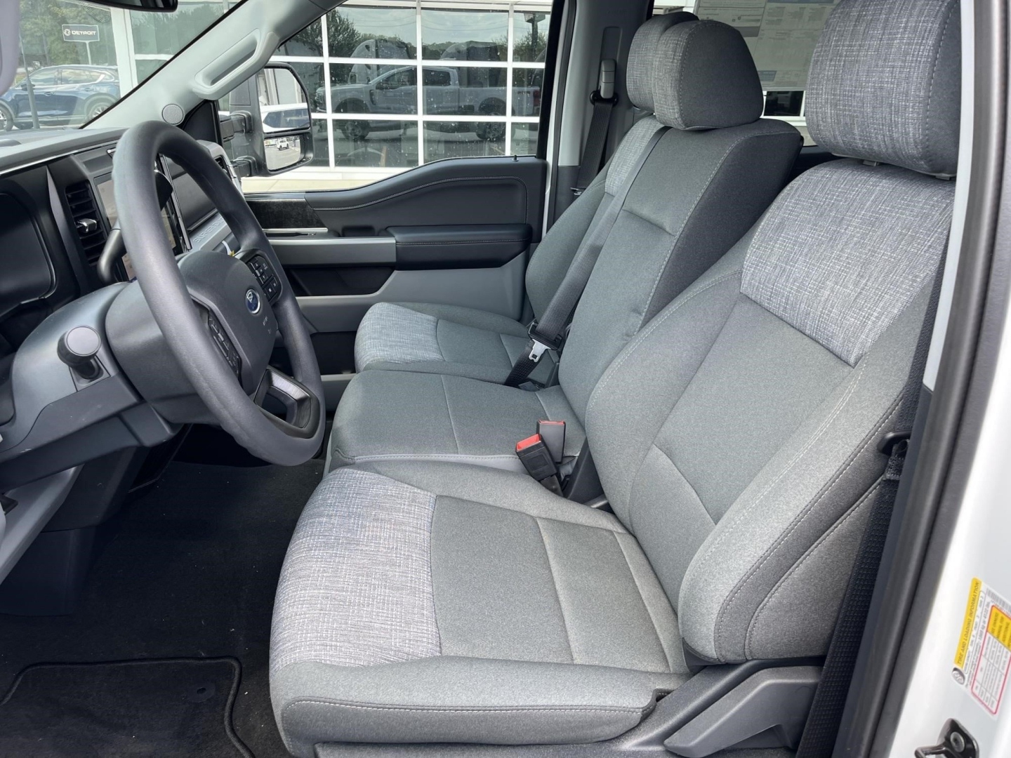 Ford F-350 pickup interior front seats and steering wheel, gray cloth seats, 3-person front bench, dashboard, and door panel; shows driver and passenger seats with center console not visible.