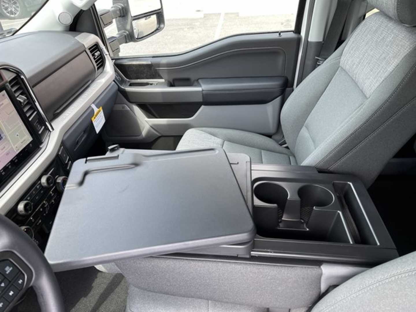 Ford F-350 interior front cabin with center console extension opened showing dual cup holders and storage tray.