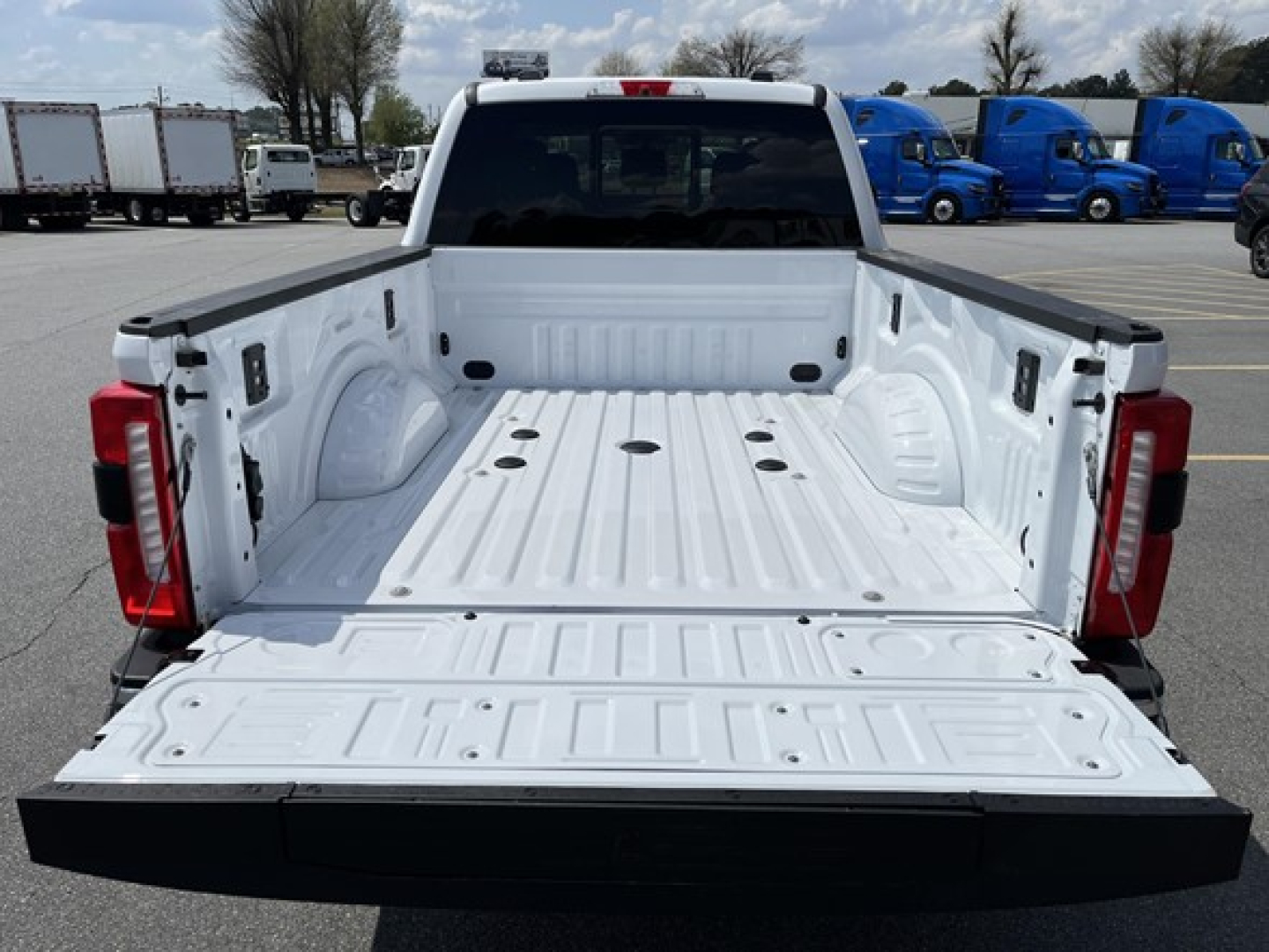 Ford F-350 pickup bed view from tailgate area showing empty cargo bed with tie-down hooks and rear taillights.