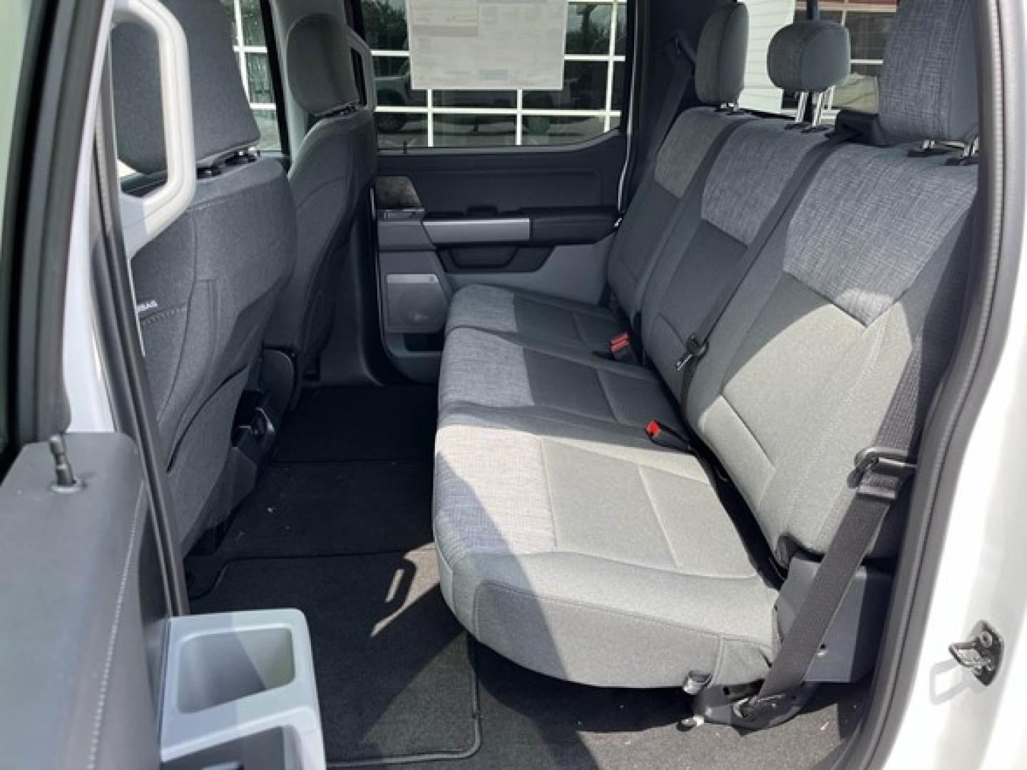 Ford F-350 pickup truck interior rear seat view showing gray cloth bench seats and rear cup holder area.