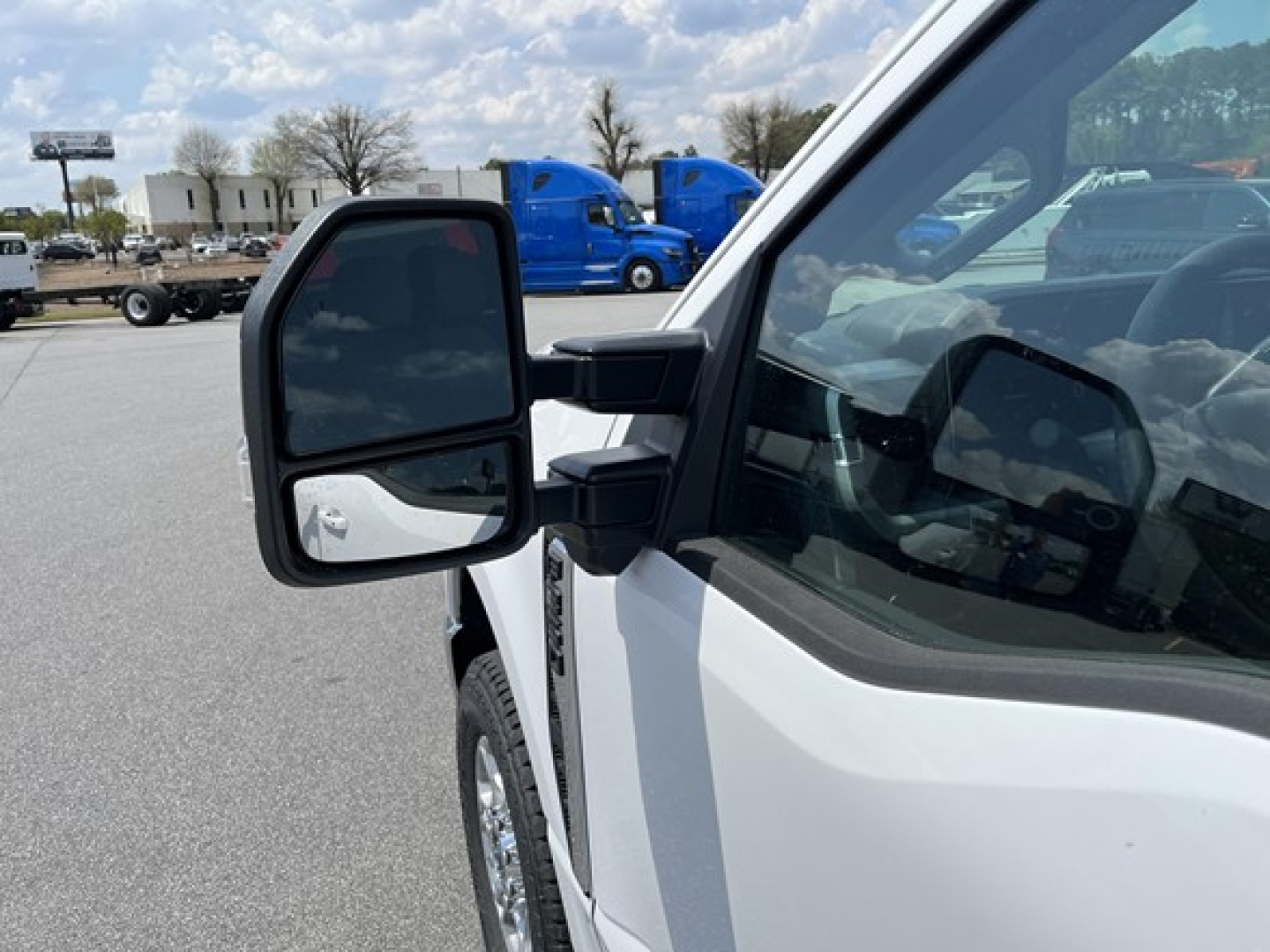 Ford F-350 pickup truck mirror and front cab area showing side mirror and part of door, white paint.