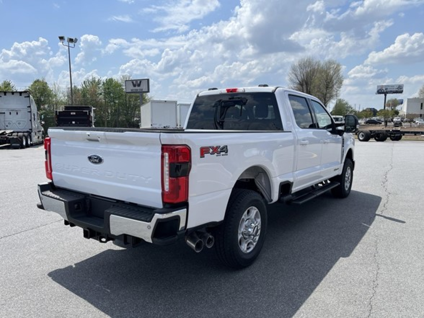 Ford F-350 Super Duty pickup truck rear three-quarters view showing FX4 badge, dual rear exhaust, white exterior, long bed.