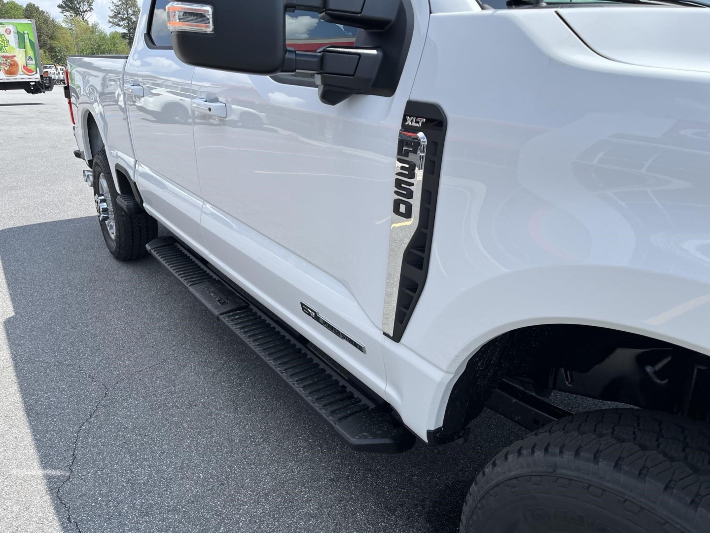 Ford F-350 Super Duty XLT badge on white pickup side view showing running board and door panel.
