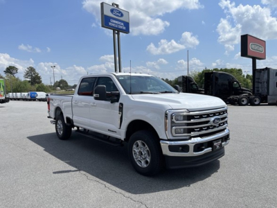 Front-left side view of a white 2026 Ford F-350 pickup truck in a dealership lot. The truck features a chrome grille, dual mirrors, running boards, and four doors with a long bed.